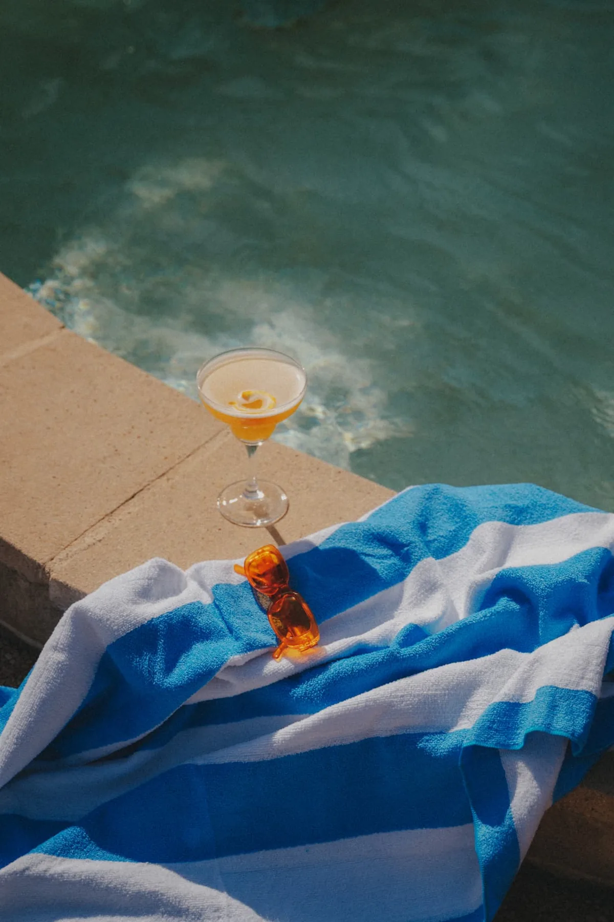 Cocktail et serviette rayée au bord de la piscine