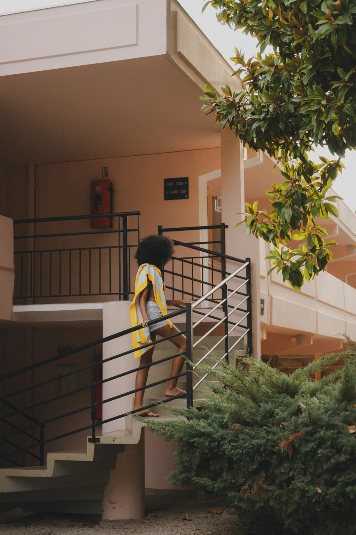 Guest climbing the Motel stairs, striped towel over her shoulder